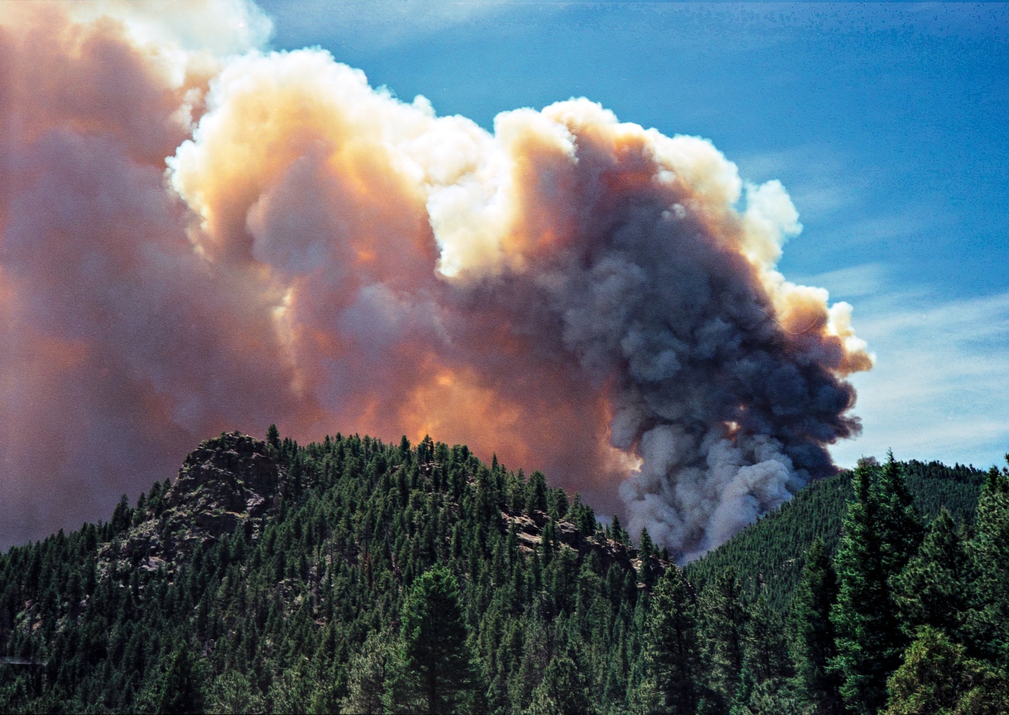 Large wildfire smoke column rising above a forested ridge along the South Platte River during the Hi Meadow Fire, Colorado, 2000